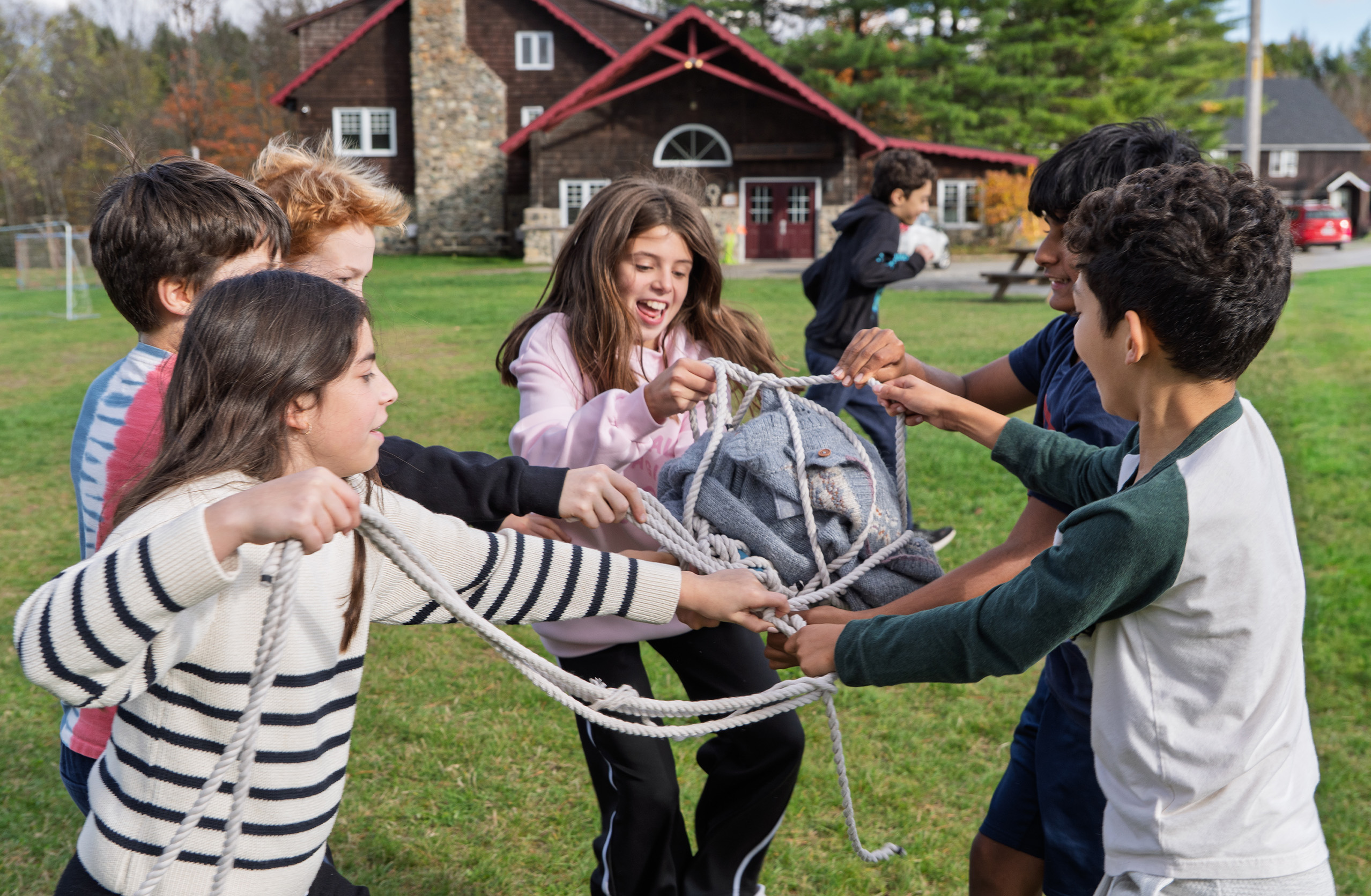 Six students play with ropes outside as part of a leadership challenge.