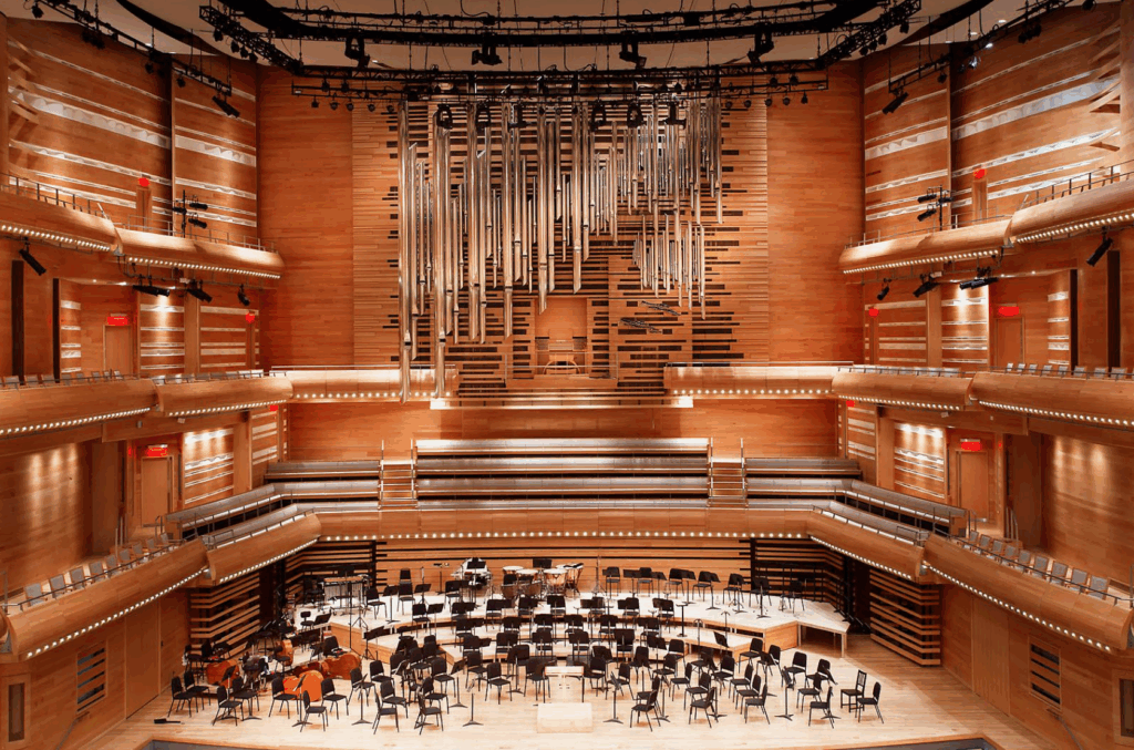 An empty synphony concert hall with musician chairs and stands faces the stage.