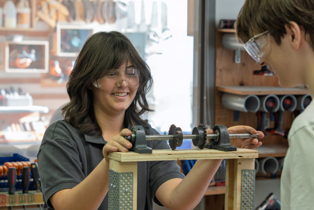 A female student measures in the robotics shop.