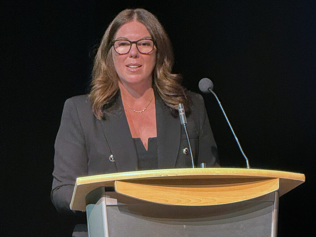 Woman stands at podium.