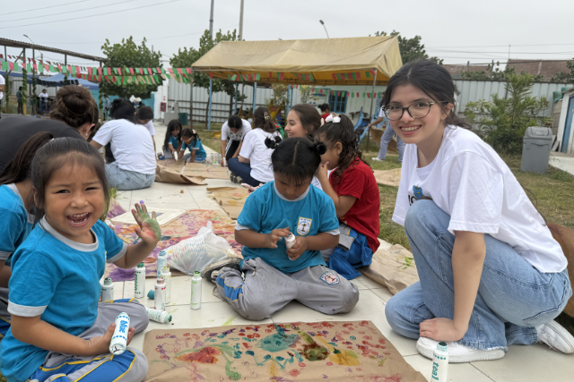 Teen with peruvian children doing an art project.