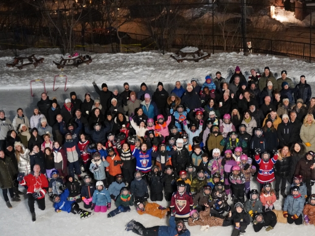 Seen from above a crowd of people are gathered together on a skate rink at night.
