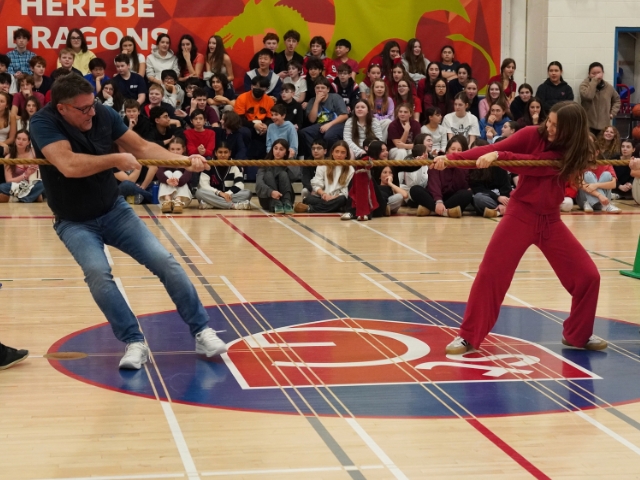 Student and teacher play tug-of-war in a gym.