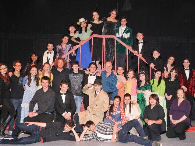 students in a play stand on stage.