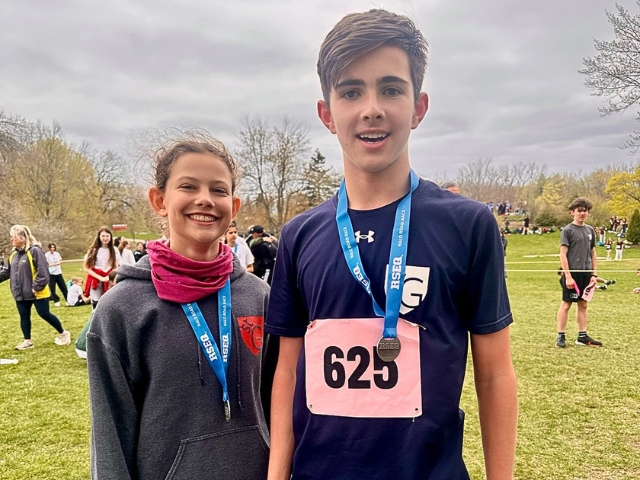 Two high school students stand with medals.