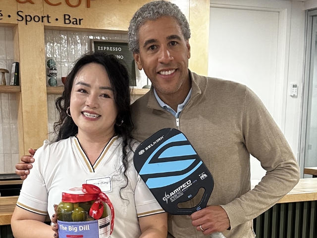 Two adults with a pickle jar and pickleball rackets.
