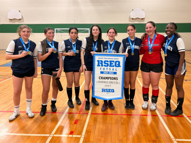 Futsal girl champions pose with a banner in the gym.