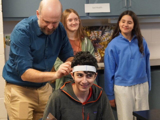 A man secures an EEG on a student's head.