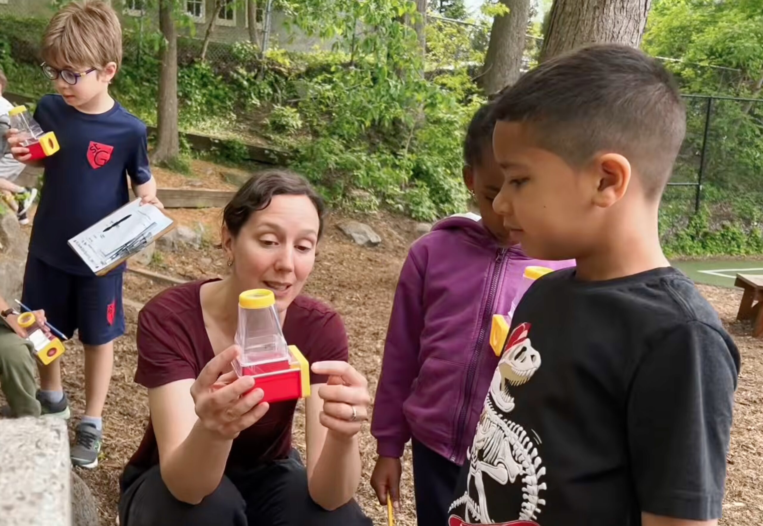 A woman shows a student insects outdoors.
