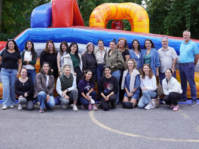 A group of adults stand in front of a bouncy castle.